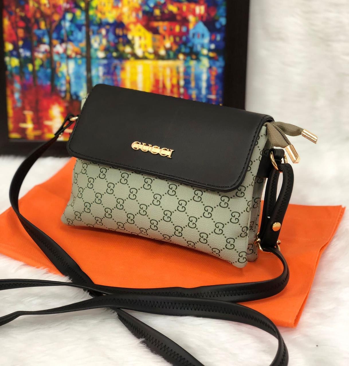 Black and beige bag is a faux-leather and coated-canvas sling bag featuring a monogram print and a black flap closure.